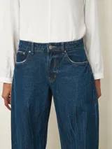 Jean de corte recto y tiro medio, con un acabado de lavado oscuro y efecto de textura sutil en la tela. Presenta cierre frontal con botón y bolsillos clásicos.