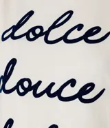 Remera color crema de algodón con cuello redondo y mangas cortas abullonadas. Estampa frontal con la frase "dolce douce dulce" en letras cursivas azul marino.