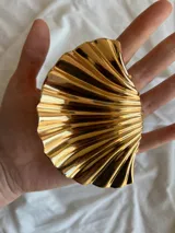 Pinza dorada para el pelo con forma de concha de mar.