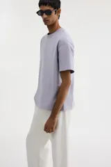 Remera de punto de algodón pesado, color lila claro, con cuello redondo ribeteado, hombros caídos y bajo recto. Corte holgado.