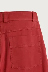 Pantalón wide fit color rojo terracota, con pliegues frontales, bolsillos laterales y cierre frontal con cremallera y botón.