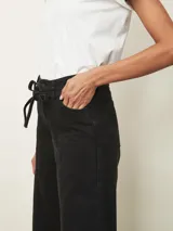 Jean de corte wide leg en color negro, con cintura alta ajustable mediante lazo y costuras verticales decorativas en el frente.