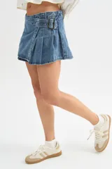 Minifalda de jean negra con diseño cruzado, cierre de hebilla metálica y detalle de tablones plisados en el lateral.