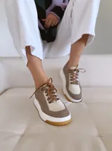 Championes de cuero color visón con cordones marrones, suela blanca y base color caramelo.