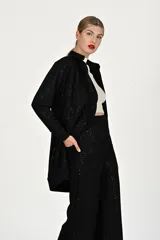 Conjunto de dos piezas en color negro con sutiles destellos brillantes. El saco es de corte recto, tipo cárdigan, con solapas y bolsillos frontales. El pantalón es de corte amplio y tiro alto.