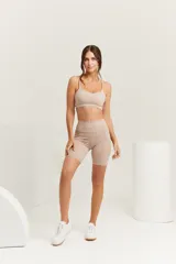 Top deportivo color beige, con breteles regulables, espalda recta y logo ZN.