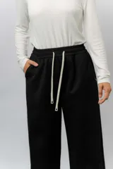 Pantalón deportivo de corte wide leg con caída relajada. Presenta cintura elastizada con cordón ajustable, bolsillos laterales y un interior frizado para mayor abrigo.