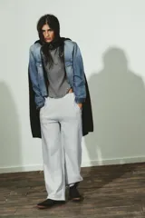 Camiseta de manga larga color gris con efecto lavado, cuello redondo y bajo redondeado. Presenta aplicaciones de tachas metálicas alrededor del escote y en el bajo.