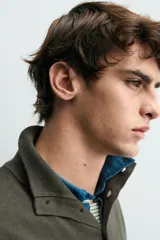 Jersey de punto de corte regular, con cuello perkins y cierre frontal parcial con botonadura. Presenta manga larga y acabados en rib en puños y bajo.