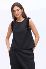Musculosa negra con cuello redondo y detalles de volados en los hombros, confeccionada en una mezcla de algodón y Tencel.