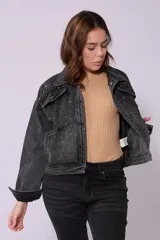 Campera de jean de lavado celeste claro, con diseño clásico de cuello y botones metálicos. Presenta detalles de pequeños brillos o tachas plateadas sobre la tela, especialmente visibles en los bordes de los bolsillos y costuras.