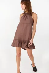 Vestido corto verde militar de lino, con escote halter fruncido en el cuello y detalle de volados en el ruedo.