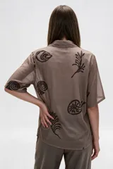 Camisa de algodón con estampado en tonos claros sobre base azul oscura, cuello solapa, mangas cortas y cierre frontal con botones.