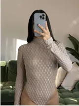 Body de manga larga y cuello alto, color tostado, con diseño de espalda descubierta y tejido texturado con patrón geométrico tridimensional.