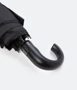 Paraguas plegable de color negro, con estructura metálica y mango curvo de plástico negro.