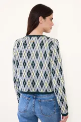 Saco de punto con diseño de rombos en tonos verde, amarillo y gris. Presenta cuello redondo, cierre frontal con botones y dos bolsillos delanteros con terminaciones en contraste.
