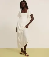 Vestido largo blanco de tejido laise con textura plisada vertical, escote cuadrado y mangas cortas con volado.