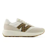 Championes urbanos New Balance modelo 370, con diseño en tonos beige y blanco. Presentan el logo lateral característico con estampado animal print de leopardo, confeccionados en una combinación de materiales textiles y gamuza, con suela de goma color caramelo.