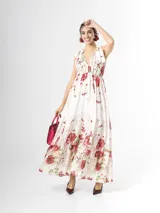 Vestido largo confeccionado en mezcla de tencel y lino, con fondo off white y estampado floral en tonos rosados, rojos y verdes. Cuenta con escote en V pronunciado, breteles anchos ajustables con lazos en los hombros, corte bajo el busto y falda amplia con volados escalonados.