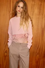 Sudadera crop de cuello redondo y manga larga con puños elásticos. Presenta un diseño de doble capa con un top interior satinado y un bajo decorado con encaje a tono.