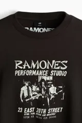 Buzo negro de cuello redondo con estampa frontal inspirada en la banda Ramones, hombros caídos y corte holgado.