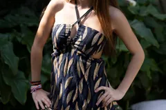 Vestido corto negro con escote en V, breteles finos cruzados en la espalda, abertura en la cintura y falda con volados.