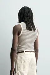 Camiseta sin mangas de corte regular, confeccionada en tejido de algodón con elasticidad. Presenta un diseño de rayas horizontales finas, cuello redondo y acabados en vivo doble.