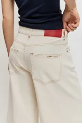 Pantalón denim de corte wide leg, tiro alto y color crudo con costuras en contraste.