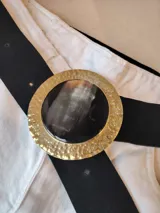 Cinto de cuero negro con hebilla circular dorada con centro de carey.