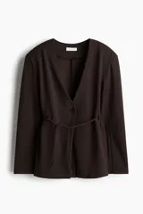 Blazer marrón de botonadura sencilla en punto roma, con cuello en V, cierre de un botón y hombreras. Presenta un cinturón fino para atar en la cintura y diseño sin forrar.
