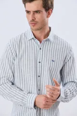 Camisa de manga larga de lino y algodón, con diseño de rayas verticales en tonos celestes y blancos. Presenta cuello camisero, cierre frontal con botones y pequeño bordado al tono en el pecho.