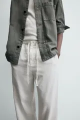 Pantalón de corte regular fit confeccionado en mezcla de algodón y lino. Presenta cintura elástica con cordón ajustable, cierre frontal con cremallera y botón, bolsillos laterales y bolsillo trasero de vivo con botón.
