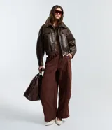 Pantalón de corte barrel con piernas anchas y cintura elástica, confeccionado en tejido técnico de poliéster y poliamida.