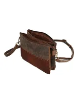 Cartera tipo bandolera de diseño rectangular, confeccionada en una combinación de cuero liso en la parte superior y cuero con pelo en la parte inferior, unidos por costuras decorativas visibles. Cuenta con correa ajustable y extraíble, cierre superior de cremallera y herrajes metálicos en tono bronce envejecido.