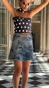 Falda corta de denim con lavado ácido (acid wash) y ruedo desflecado. Presenta un corte acampanado y cierre metálico en el costado.