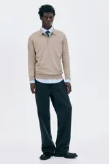 Remera polo de manga larga en punto fino color beige, con cuello clásico y tapeta de dos botones. Presenta remates acanalados en puños y bajo.