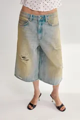 Bermuda de denim de tiro medio y corte baggy, con diseño de cinco bolsillos, trabillas para cinto y rotos decorativos.