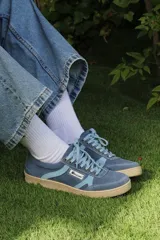Zapatillas urbanas de diseño retro en tonos beige, marrón y celeste, confeccionadas en serraje con suela de goma color caramelo y cordones blancos.
