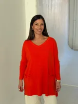 Sweater de punto color naranja, con cuello en V, manga larga y diseño holgado con bolsillos frontales y tajos laterales.