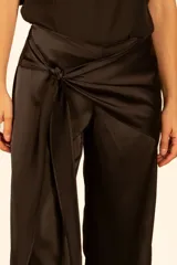 Pantalón negro de satén con corte palazzo, tiro alto y lazo lateral en la cintura.
