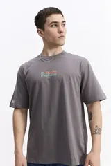 Remera de manga corta color celeste claro, con cuello redondo y estampado gráfico grande en la espalda con la palabra "BLESSED" y frases como "BE GRATEFUL EVERY MOMENT". Incluye el logo de la marca Mistral.