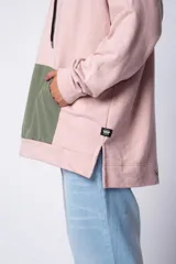 Buzo tipo canguro con capucha, confeccionado en una combinación de algodón rústico y microfibra. Presenta un diseño bicolor en tonos rosado y verde militar, con bolsillo frontal tipo canguro en contraste, cordones ajustables y estampa personalizada en el frente.