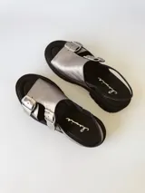 Sandalias de cuero color peltre con plataforma y suela track color negro. Presentan dos tiras anchas con hebillas plateadas y tira trasera ajustable.