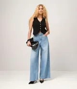 Chaleco sin mangas de tejido de punto negro, con escote en V y cierre frontal mediante una hilera de botones metálicos dorados.