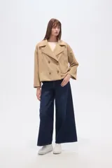 Chaqueta corta estilo peacoat, color beige, con cuello solapa y cierre cruzado de doble botonadura. Presenta un calce holgado y bolsillos laterales.
