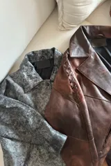 Campera bomber de cuero ovino en tono óxido, con diseño de solapas, cierre frontal con botones de guampa y detalles de pasamanería trenzada en las mangas.