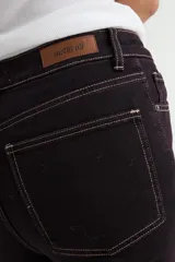 Jean de corte flare en color negro, con costuras verticales decorativas en contraste y ruedo deshilachado.