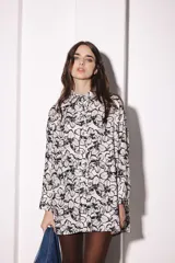 Camisa blanca con estampado floral negro, de corte amplio y mangas largas.