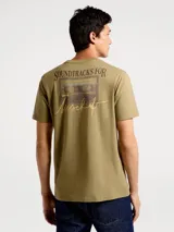 Camiseta blanca de algodón con cuello redondo y mangas cortas. Estampa rectangular con borde negro que contiene la frase "NATURAL ATMOSPHERE" en letras mayúsculas y una imagen de montañas y mar.