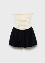 Vestido corto de diseño combinado con cuerpo strapless drapeado en color beige y falda estilo globo en color negro. Cuenta con cierre lateral invisible.